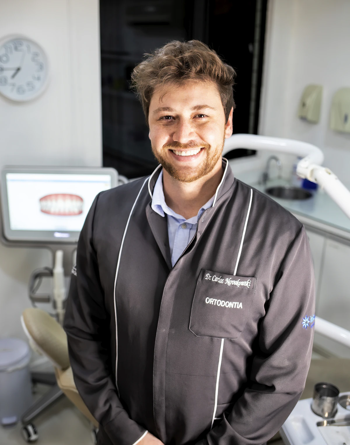 Dentista sorrindo em um consultório claro e moderno